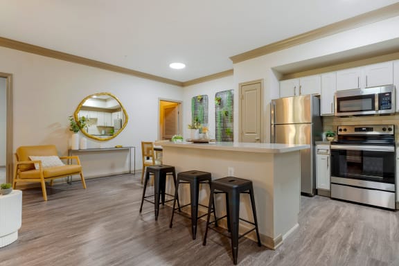 a kitchen with a large island with three stools at Summerwind in Pearland, TX
