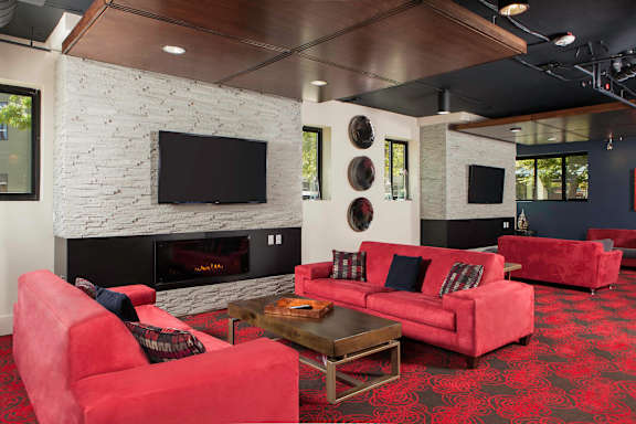 A spacious living room with a wooden ceiling and grey carpet.