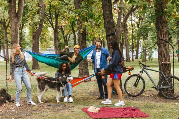 A group of people in a park with a hammock and a dog at Riverhouse Apartments, Fargo, ND 58102