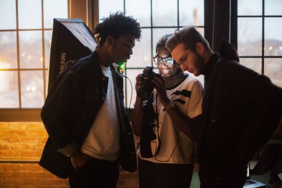 three people looking at a camera in front of a window