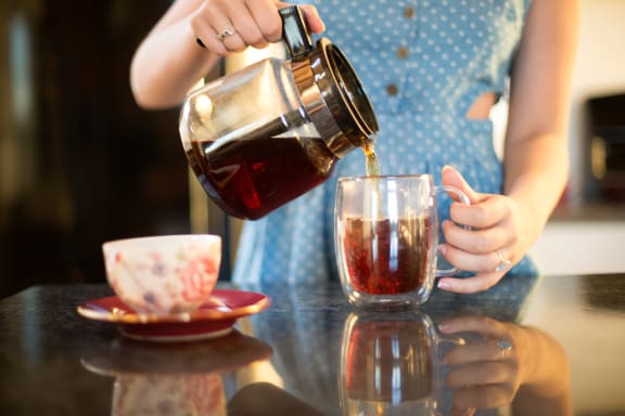 a woman is pouring tea into a mug on a table