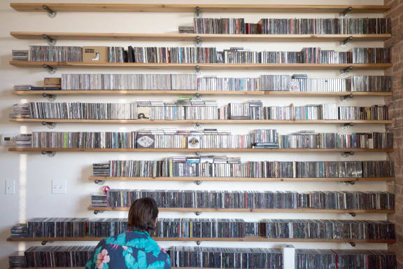 a woman standing in front of a wall full of dvds