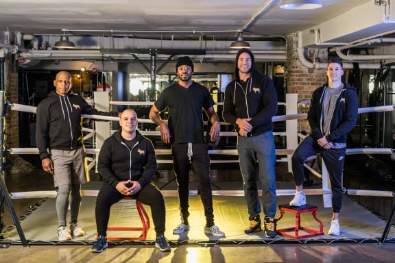 a group of men standing in front of a boxing ring