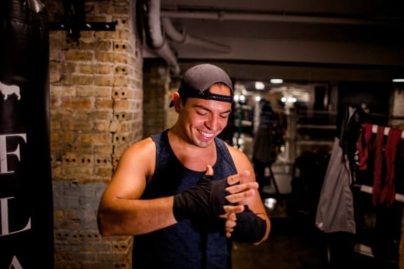 a man wearing gloves and a hat laughing in a gym