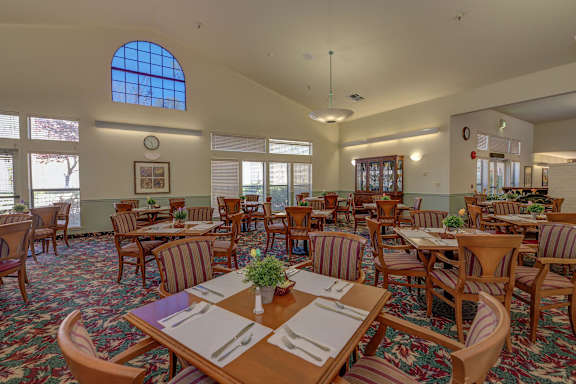 Community dining room with table settings and natural light at Hilltop Commons Senior Living, Grass Valley