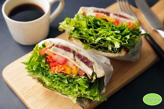 A sandwich cut in half and a cup of coffee are on a wooden board at Hampton Plaza Apartments, Towson, MD, 21286