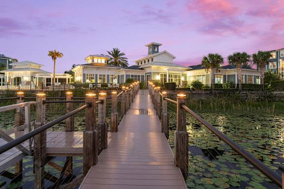 A wooden pier leads to a row of houses by the water.
