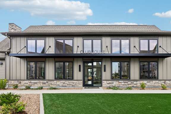 A clubhouse with a stone facade and a green lawn in front.