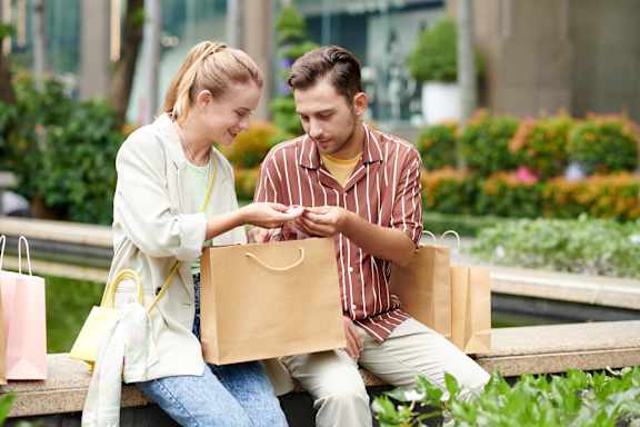 A man and a woman are sitting on a bench with shopping bags at The Union Flats at Fishers District, Indiana