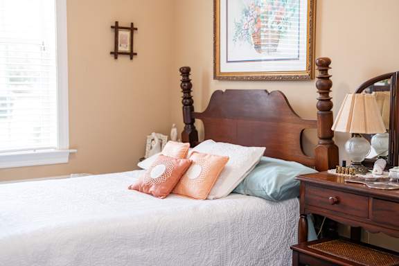 a bedroom with a bed with two pillows and a dresser with a lamp