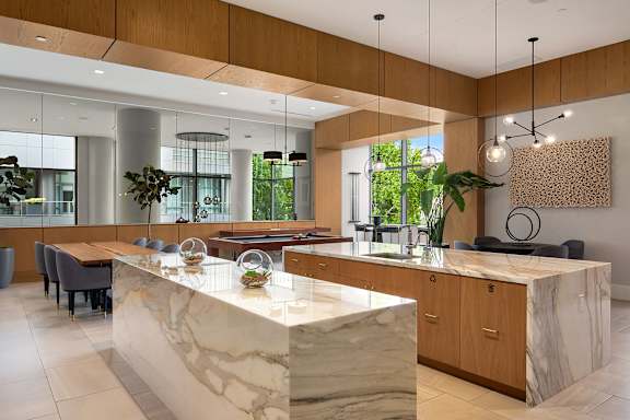 A modern kitchen with a marble island and wooden cabinets.