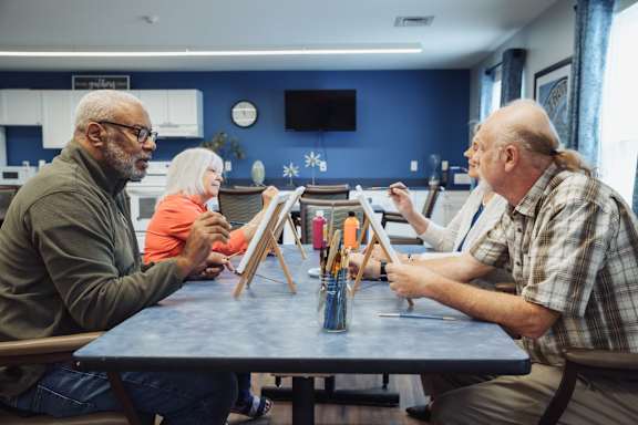 Three people are painting at a table.