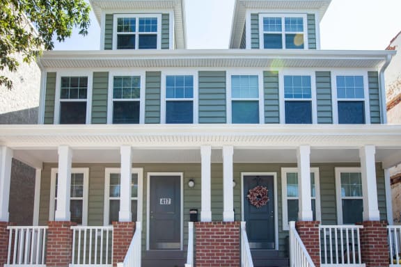 the front porch of a home with blue shutters and a black door