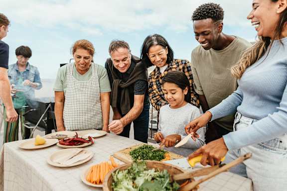A group of people are gathered around a table, preparing food together.