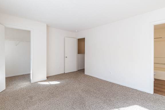 A white room with a carpeted floor and a door.