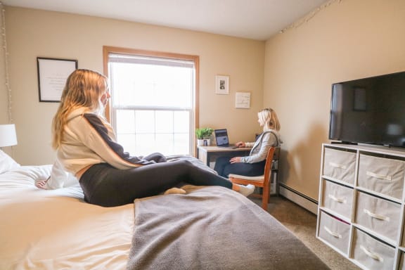 two women sitting on a bed in a room with a desk at Summit Ridge, Duluth, MN, 55811