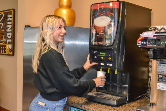 a woman holding a cup of coffee in a coffee machine at Summit Ridge, Duluth, MN