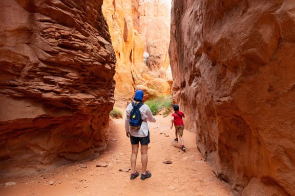 a man and two children walking through a slot canyon