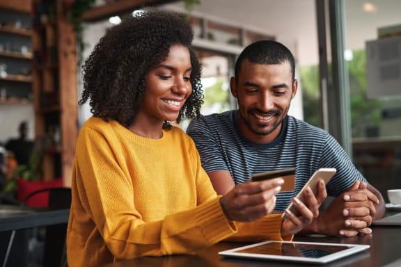 two people sitting at a table looking at a cell phone