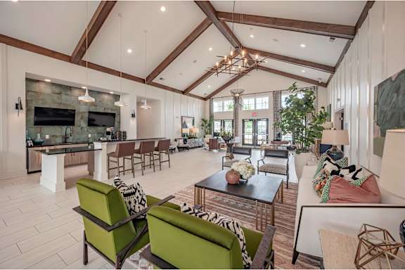 A modern living room with a stone fireplace and a large green sofa at Waterleaf at Neely Ferry Apartments, Simpsonville, SC