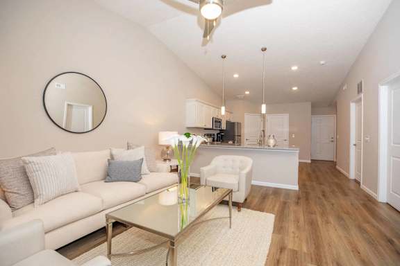 A modern living room with a glass coffee table and a white couch.