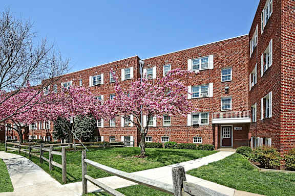 A red brick building with a tree in front of it.