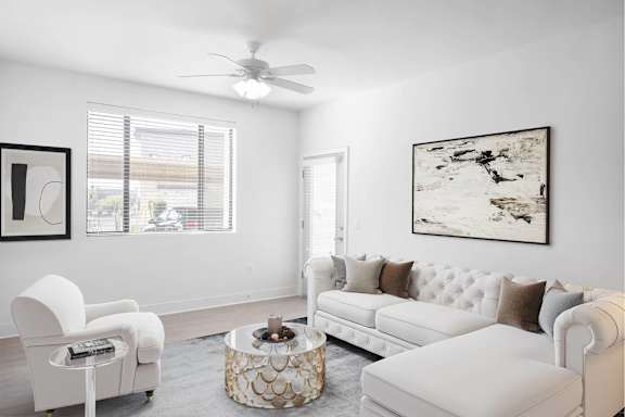 A living room with a white sofa, a white chair, and a coffee table with a decorative design.