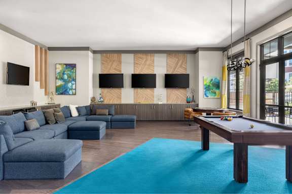 A living room with a pool table and a blue rug.