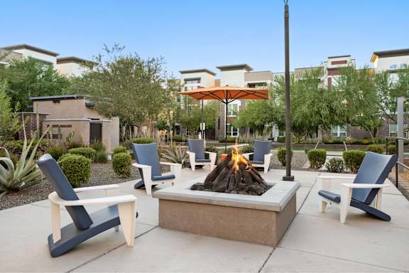A patio with a fire pit and chairs.