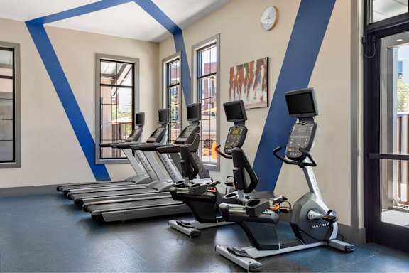 A gym with treadmills and a clock on the wall.
