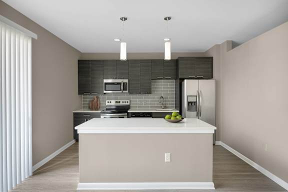 A modern kitchen with a white island and stainless steel appliances.
