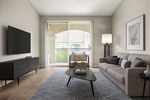 A living room with a grey couch, a black cabinet, a black coffee table, and a flat screen TV.