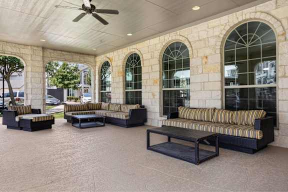 A patio with a striped couch and a ceiling fan.