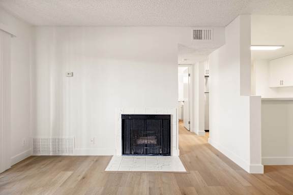 A large, empty room with a fireplace at the center.