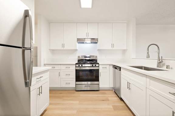 A modern kitchen with white cabinets and stainless steel appliances.