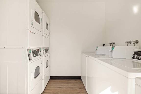 A row of washing machines and dryers in a laundromat.