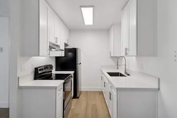 A kitchen with black appliances and white cabinets.