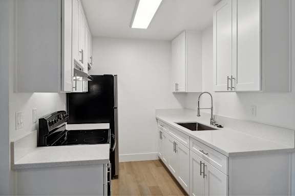 A kitchen with white cabinets and a black oven.