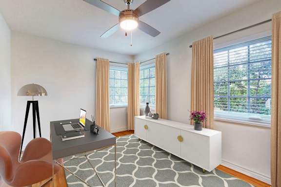 A room with a table, chairs, and a ceiling fan.