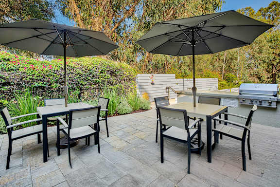 A patio with a table and chairs under umbrellas.