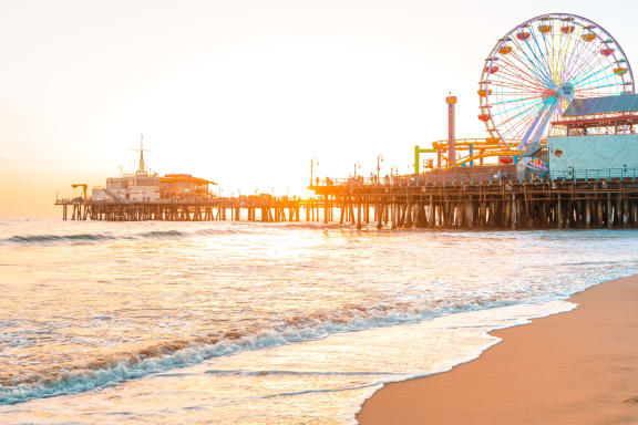 a ferris wheel on the Santa Monica pier on the beach at sunset at West Park Village, Los Angeles, California