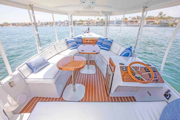 A boat's deck with a table and chairs overlooking the water.