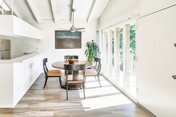 a dining room with a wooden table and chairs and a kitchen with glass doors at Mediterranean Village Costa Mesa, Costa Mesa, California