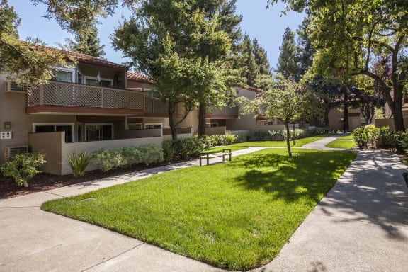 a sidewalk in front of an apartment building with grass and trees at Valley Plaza Villages, Pleasanton, 94566