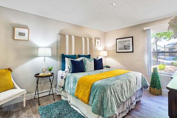 A bedroom with a bed, nightstand, and a chair.
