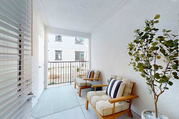 A balcony with two chairs and a table with a tree in a pot.