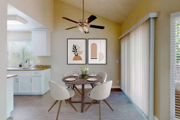 A dining room with a table set for two and a ceiling fan.