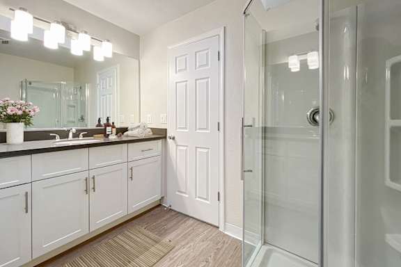 A bathroom with a white door and a glass shower.