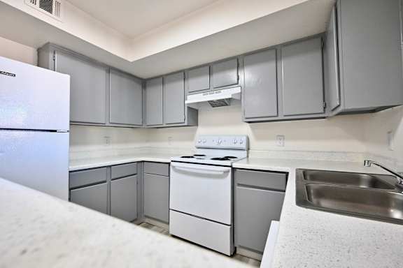 A kitchen with a white fridge, stove, and dishwasher.