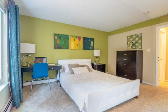 A bedroom with a white bed and a blue chair.